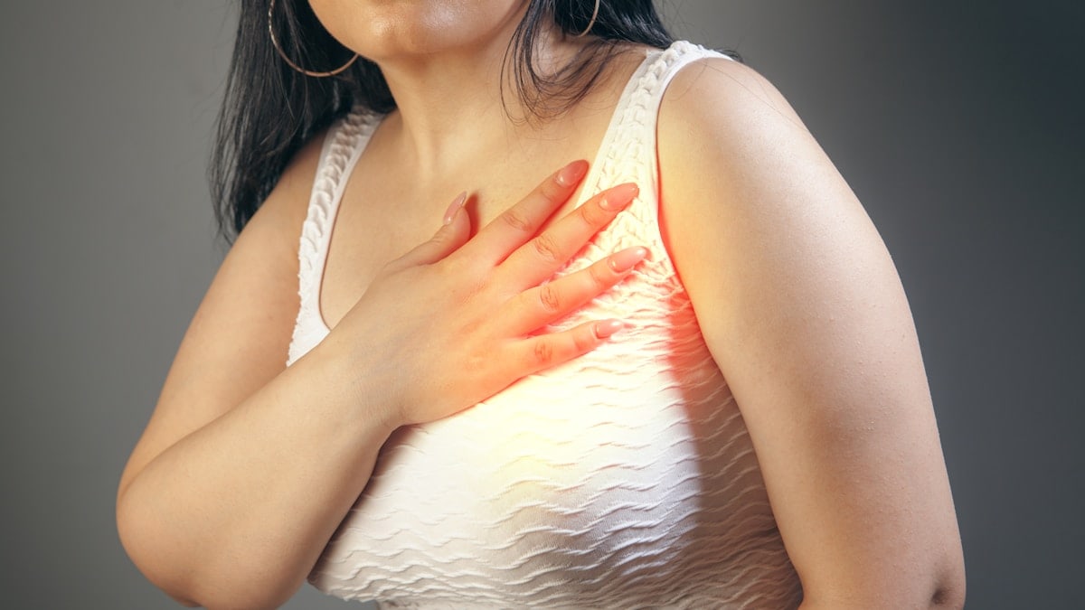 Woman suffering from chest pain on a gray background. Health care concept.